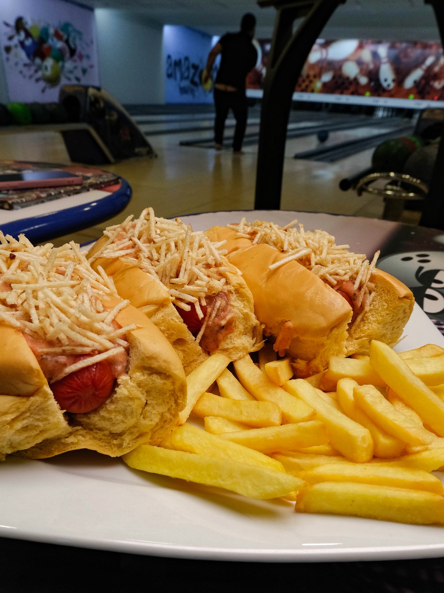 Hot dogs com batata frita servidos ao lado das pistas